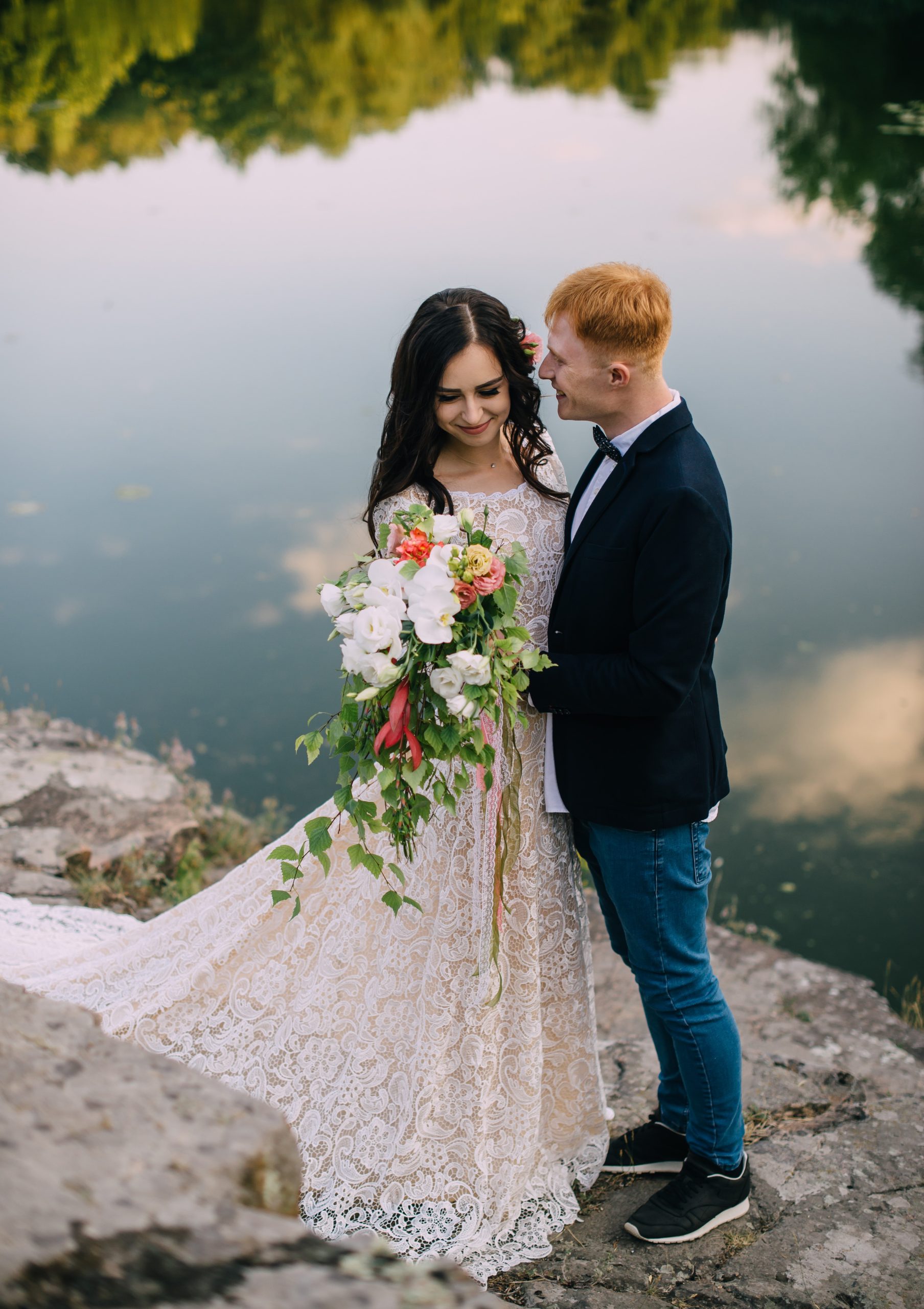Happy newlyweds standing and smiling on the river bank